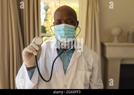 Portrait of senior african american male doctor in face mask holding stethoscope Stock Photo