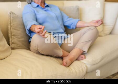 Mid section of senior caucasian woman sitting on sofa meditating Stock Photo