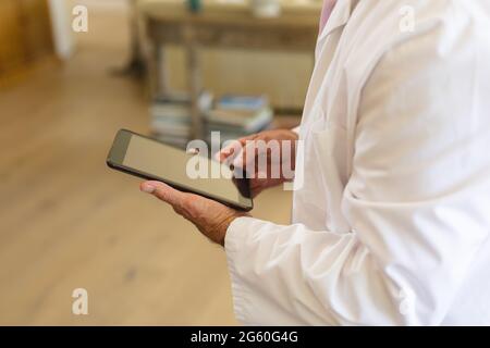 Senior caucasian male doctor using tablet computer in living room Stock Photo