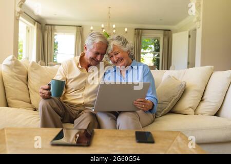 Senior caucasian couple sitting on sofa using laptop Stock Photo