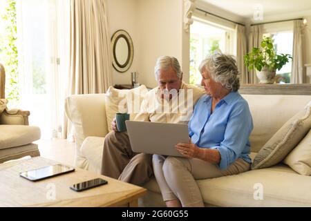 Senior caucasian couple sitting on sofa using laptop Stock Photo