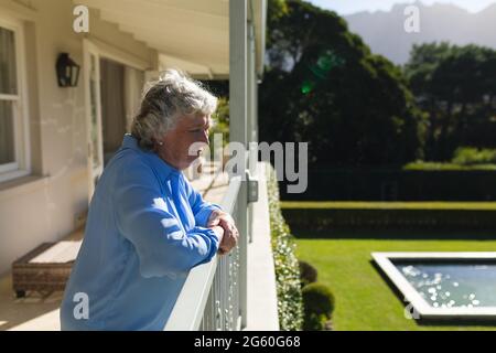 Senior caucasian woman standing on balcony and looking away Stock Photo