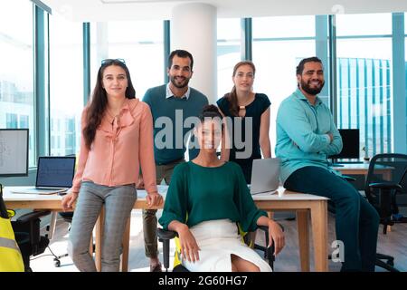 Portrait of group of diverse businesspeople smiling together and sitting at table Stock Photo