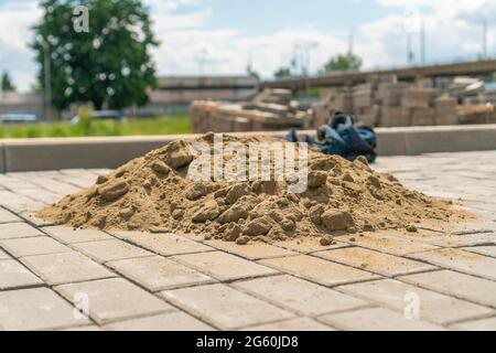 Close-up of a pile of sand lying on the new sidewalk to seal the seams between the paving slabs. Laying of paving slabs Stock Photo