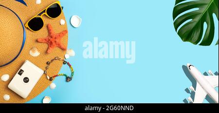 Travel summer background. Sunglasses, hat, palm tropical leaves, seashells, airplane and beach accessories on a colored blue background. Tourist vacation, relaxation and summer concept. High quality photo Stock Photo