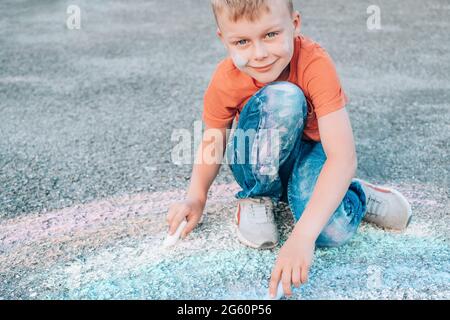 Cute boy drawing with chalk on the pavement. High quality photo Stock Photo