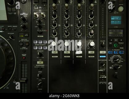 Upper view closeup of dj musical mixer professional console black color with many buttons and knobs in night club or studio on digital background Stock Photo