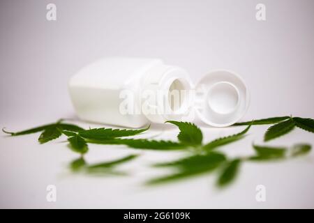 white jar with cannabis leaves on a white background. Stock Photo