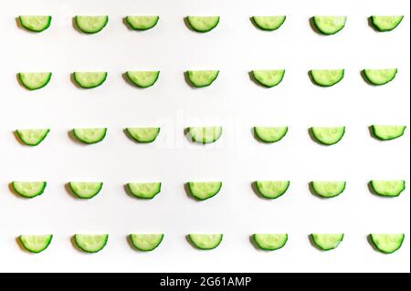 repeating pattern of sliced semicircles of fresh raw vegetable cucumbers for salad isolated on a white background flat lay, top view Stock Photo