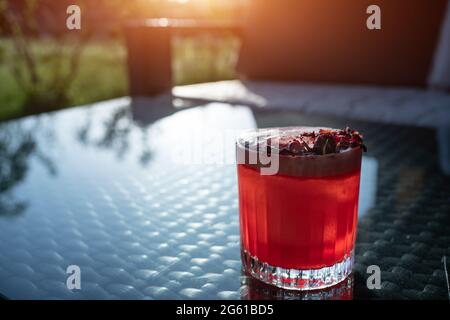 clover club cocktail drink with raspberry and rose petal outdoor at sunset Stock Photo