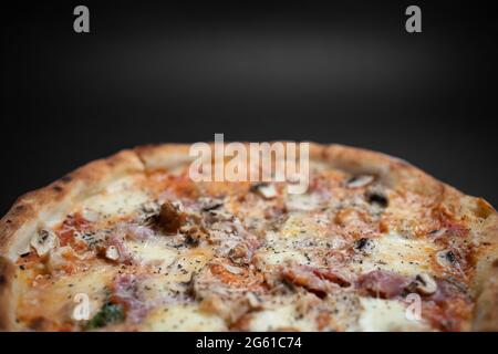 closeup of italian pizza with ham, mushrooms and cheese on black background Stock Photo