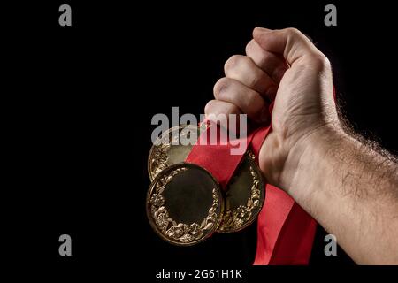 hand holding a gold medal on black with blank face for text, concept for winning or success Stock Photo