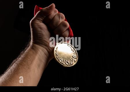 hand holding a gold medal on black with blank face for text, concept for winning or success Stock Photo