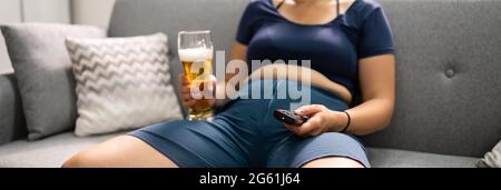 Overeating Junk Food, Drinking Beer And Watching TV Stock Photo