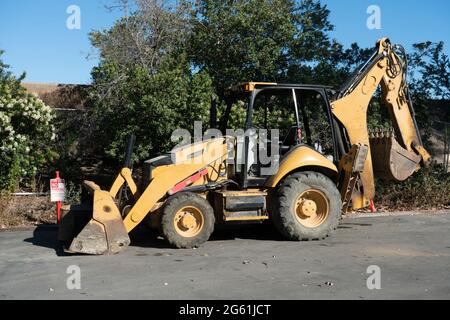 Construction backhoe loader parked on asphalt lot. Stock Photo