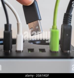 Modern convenient multi-port usb charger for devices. Close-up of inserted multi-colored cables in a power outlet. Macro. Stock Photo