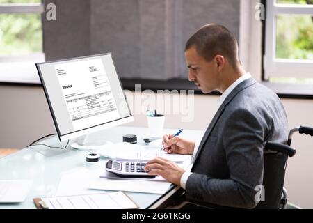 Disabled Accountant In Wheelchair Working Using Computer Stock Photo