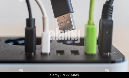 Modern convenient multi-port usb charger for devices. Close-up of inserted multi-colored cables in a power outlet. Macro. Stock Photo