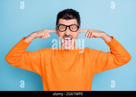 Portrait of negative person fingers in ears open mouth scream loud fuming isolated on blue color background Stock Photo