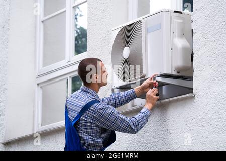 Technician Cleaning And Repairing Air Condition Appliance. AC Unit Maintenance Stock Photo