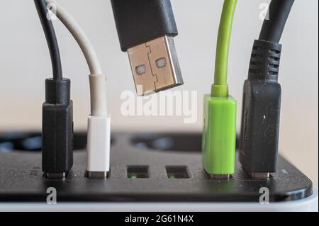 Modern convenient multi-port usb charger for devices. Close-up of inserted multi-colored cables in a power outlet. Macro. Stock Photo