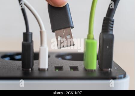 Modern convenient multi-port usb charger for devices. Close-up of inserted multi-colored cables in a power outlet. Macro. Stock Photo