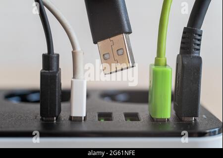 Modern convenient multi-port usb charger for devices. Close-up of inserted multi-colored cables in a power outlet. Macro. Stock Photo