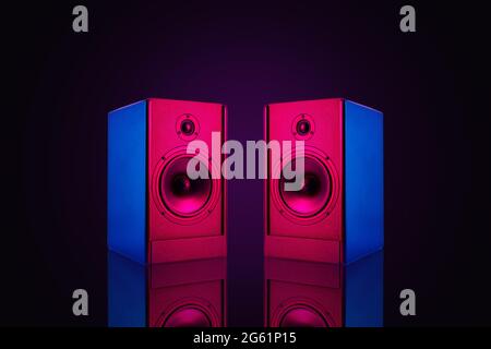 Two neon colored stereo speakers on dark background with reflection.Sound audio loud speakers, close up Stock Photo