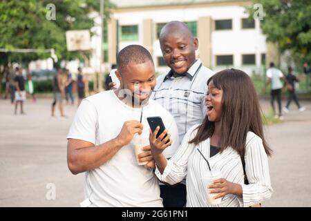 three young african people outdoor looking into their phone Stock Photo
