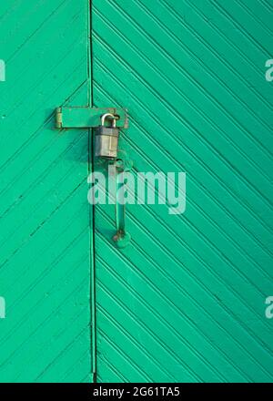 Exterior closed old green wooden doors with hanging padlock Stock Photo