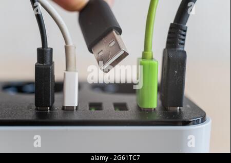 Modern convenient multi-port usb charger for devices. Close-up of inserted multi-colored cables in a power outlet. Macro. Stock Photo