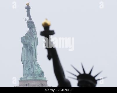 New York City, USA. July 1 2021: Lady Liberty's 'Little Sister' Statue from France stands fully installed with a view of the Statue of Liberty on Ellis Island on Thursday, July 1, 2021 in New York City. The 9-foot-tall bronze statue was crafted from the original 1878 plaster model by Auguste Bartholdi and was previously on view at Paris's Musee des Arts et Metiers. The Statue will be displayed on Ellis Island over the July 4th holiday weekend before being installed outside of the French Ambassador's Residence in Washington, DC for on Bastille Day. Stock Photo