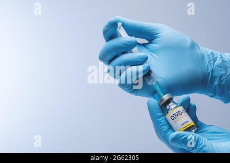 Hands in blue latex gloves with vaccine from glass vial. Healthcare And Medical concept. Stock Photo
