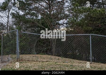A Large hole cut in to a chain link fence and nature summer Stock Photo