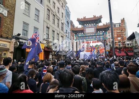 Protesters gather at the London Chinatown during the demonstration. Hongkongers held demonstrations in ten different cities in the UK to protest against the one year anniversary of the promulgation of the Hong Kong National Security Law and the Centennial anniversary of the Chinese Communist Party. In London, participants gathered outside the Chinese Embassy and marched to Chinatown where the main event took place. The crowds later moved to the Hong Kong Economic and Trade Office and set smoky flares outside as a symbolic sign of cursing the Hong Kong Government. Stock Photo