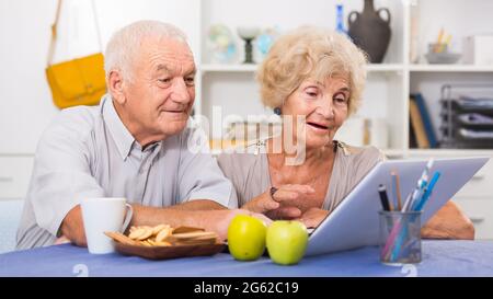 Cheerful mature spouses using laptop at home Stock Photo