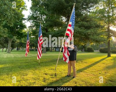 Racine, Wisconsin, USA. 1st July, 2021. A cemetery worker places American flags at the entrance to Mound Cemetery in Racine Wisconsin early Thursday (Credit Image: © Mark Hertzberg/ZUMA Press Wire Service) Stock Photo