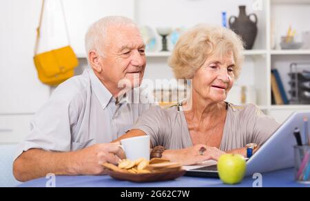 Cheerful mature spouses using laptop at home Stock Photo