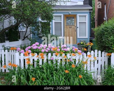 Charming small old house with white picket fence and flowers in front garden Stock Photo