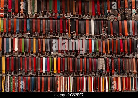 Many colored italian leather belts on display on a market. Fashion background. Stock Photo