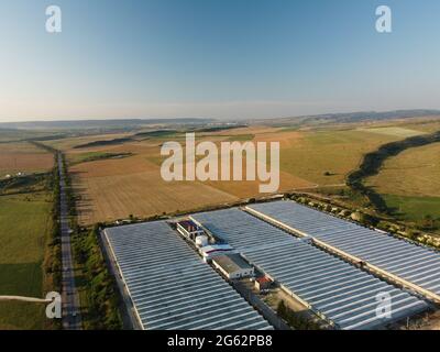 Aerial drone view of huge areas glass greenhouse for growing vegetables. Greenhouse farming, agriculture industry. Flying over large industrial Stock Photo