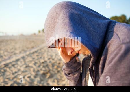 Sad Young Man in a Hoodie on the Beach Stock Photo