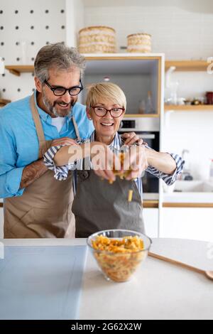Senior couple having fun, cooking in home kitchen Stock Photo