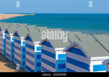 Blue and white beach cabanas with a view of the sea and beach by the seaside in Hasting's UK, on the English Channel. Stock Photo