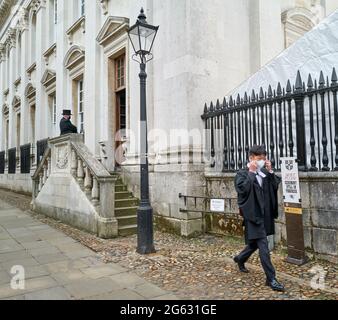 A graduate student from Trinity Hall college, university of Cambridge, England, puts on a face mask after leaving his graduation ceremony at Senate house, 1st July 2021. Stock Photo