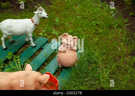 Figures of animals on the lawn. Figurines for flower bed decoration. Farm animals in the form of figurines for the yard. Stock Photo