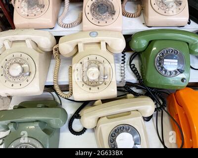 From above composition of old fashioned rotary telephones placed on white wooden shelves Stock Photo