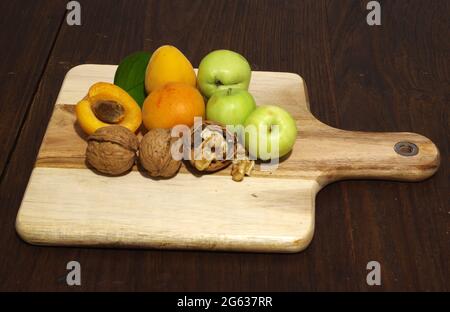 Apricots and apples with walnuts on wooden table Stock Photo