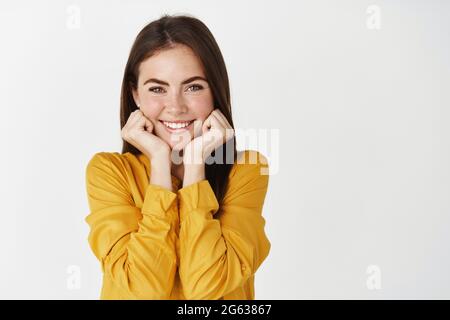 Free Photo  Beautiful girlfriend with lovely smile, lean cute face on  hands and watching something adorable, looking with admiration and  interest, listening you, standing happy against white background