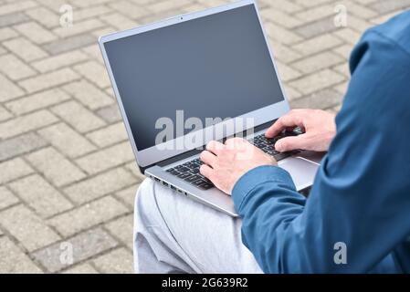 Laptop computer and man hands while working remotely on the computer outdoors.  Freelance programmer works remotely. Student using computer for learni Stock Photo